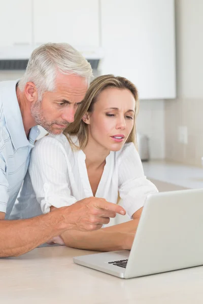 Serious couple using laptop together at the counter — Stock Photo, Image