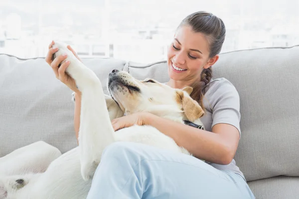 Donna felice accarezzare il suo labrador giallo sul divano — Foto Stock