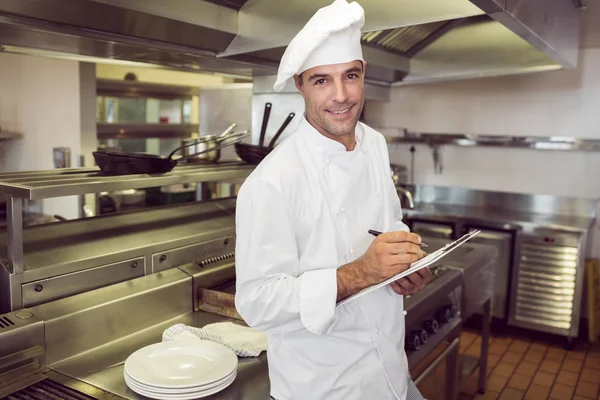 Cozinhe escrevendo na área de transferência na cozinha — Fotografia de Stock