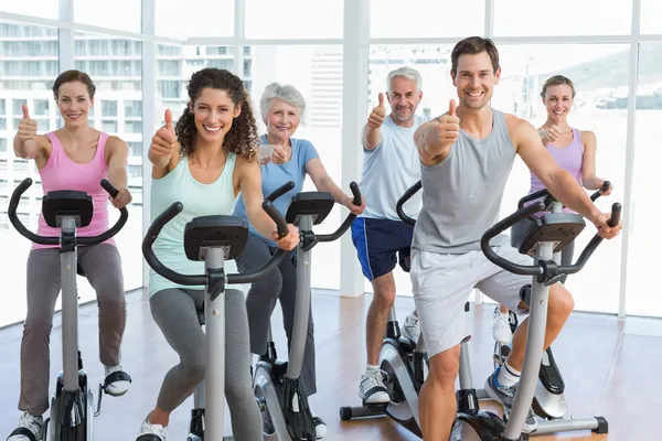 People working out at spinning class while gesturing thumbs up — Stock Photo, Image
