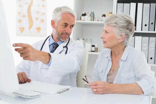 Doctor with female patient reading reports on computer — Stock Photo, Image