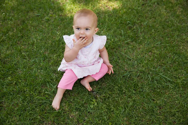 Cute baby sitting on grass at park — Stock Photo, Image