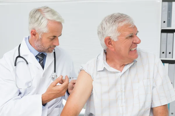 Doctor injecting senior male patient — Stock Photo, Image