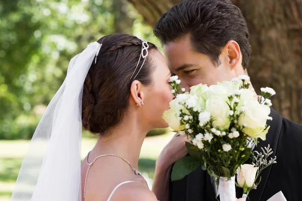 Couple kissing behind flowers in garden — Stock Photo, Image