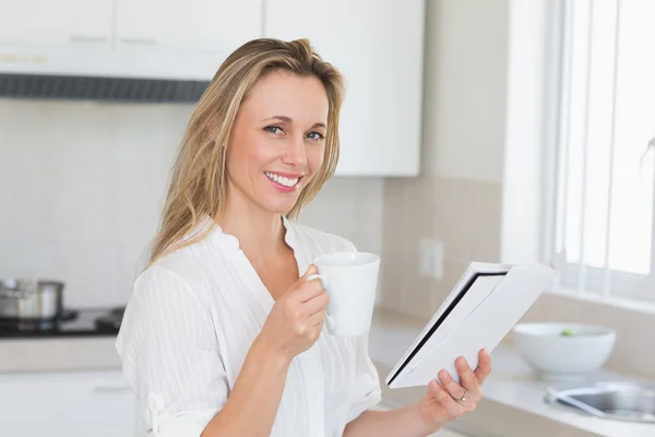 Leende kvinna anläggning mugg och tidningen — Stockfoto