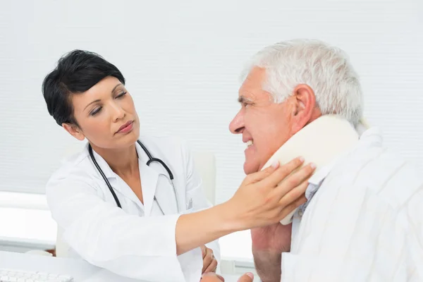 Kvinnliga läkare undersöka en äldre patienter hals — Stockfoto