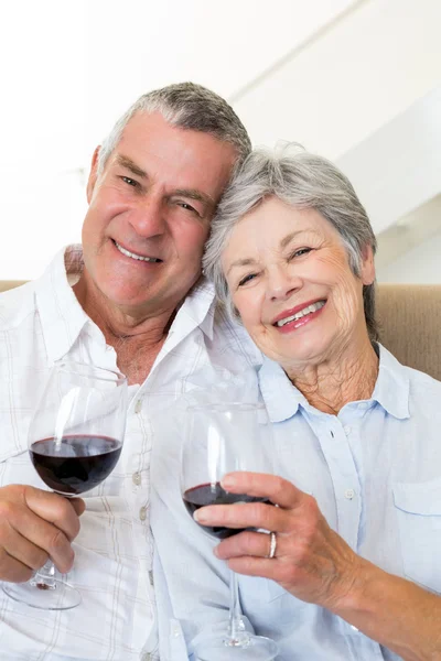 Seniorenpaar sitzt auf Couch und trinkt Rotwein — Stockfoto