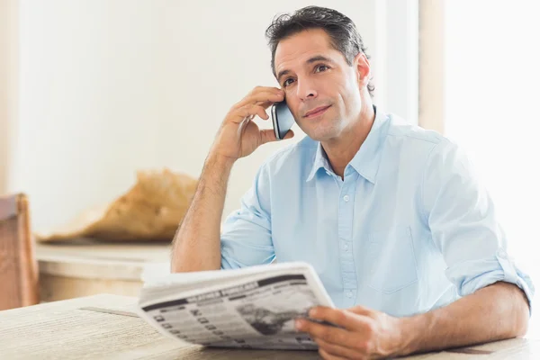 Man met krant met behulp van mobiele telefoon — Stockfoto