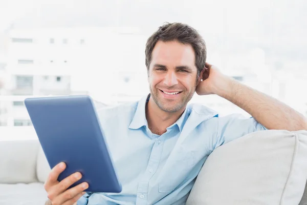 Hombre guapo sentado en el sofá utilizando su PC tableta — Foto de Stock