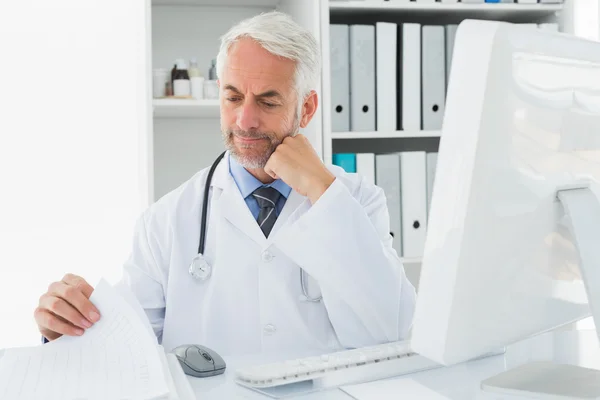Зрілий чоловік лікар з комп ютером в медичному кабінеті — стокове фото