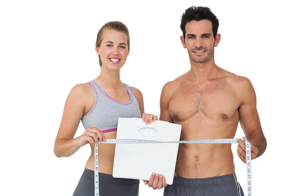 Sporty couple holding scales and measuring tape — Stock Photo, Image