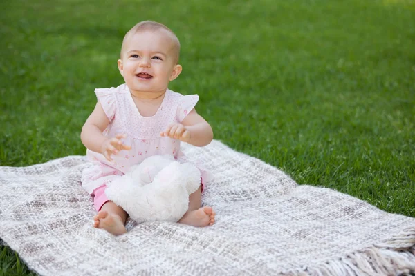 Симпатичный ребенок сидит на одеяле в парке — стоковое фото