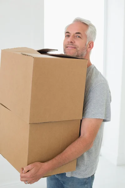 Smiling man carrying cardboard moving boxes — Stock Photo, Image