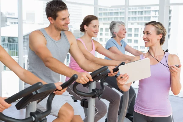 Trainer besides people working out at spinning class — Stock Photo, Image