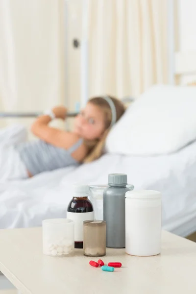 Garrafas de remédio na mesa com menina — Fotografia de Stock