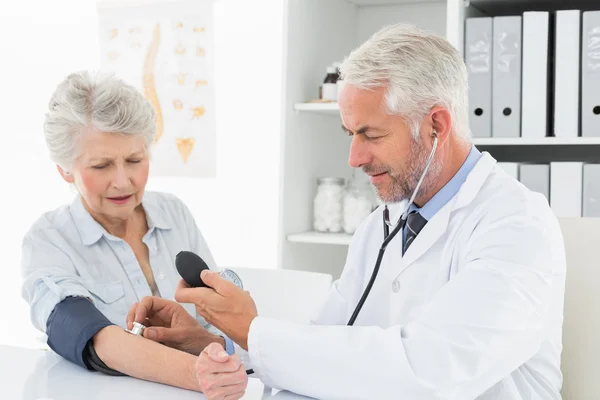 Doctor taking the blood pressure of his retired patient — Stock Photo, Image