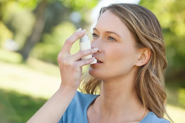 Vrouw met behulp van astma-inhalator in park — Stockfoto