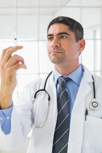 Serious male doctor holding an injection — Stock Photo, Image