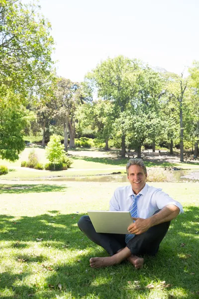 Homme d'affaires avec ordinateur portable assis dans le parc — Photo