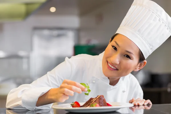 Sorrindo chef feminino guarnição de alimentos na cozinha — Fotografia de Stock