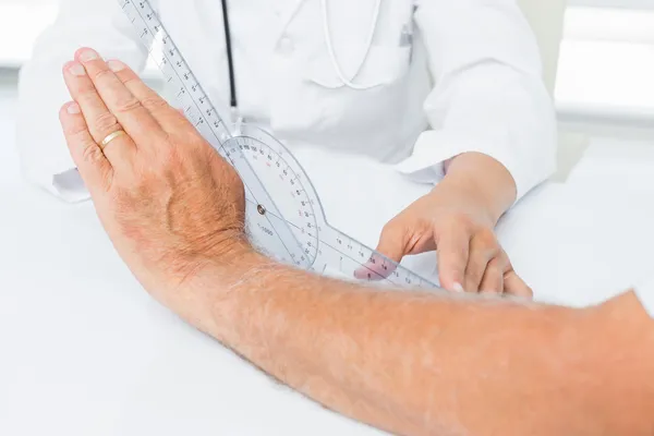 Fisioterapeuta examinando pacientes muñeca con goniómetro — Foto de Stock