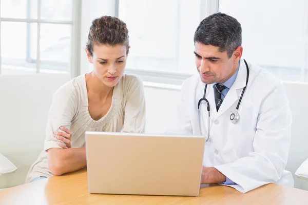 Médico y paciente usando laptop en consultorio médico —  Fotos de Stock