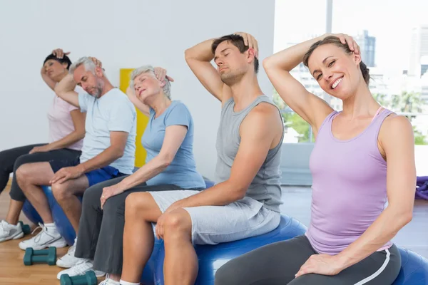 Sınıf egzersiz topları üzerinde oturan ve spor salonunda boyun germe — Stok fotoğraf