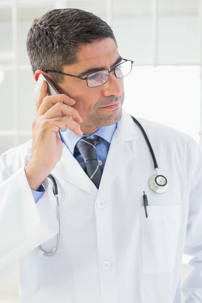 Серьезный мужчина врач с помощью мобильного телефона — стоковое фото