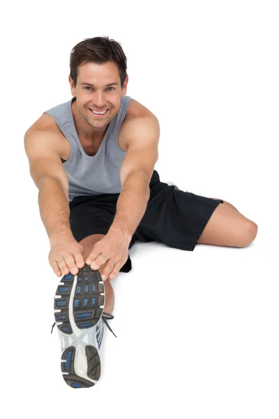 Portrait of a young man stretching hands to leg — Stock Photo, Image