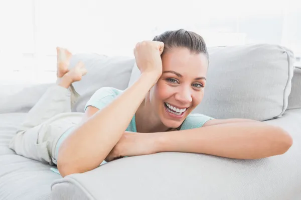 Mujer alegre acostada en el sofá sonriendo a la cámara — Foto de Stock