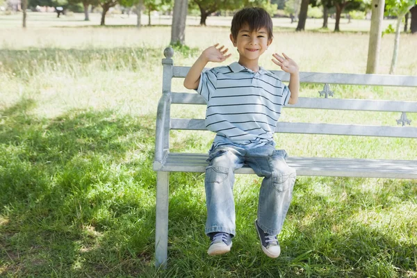 Felice giovane ragazzo seduto sulla panchina al parco — Foto Stock