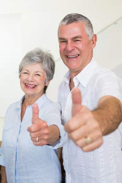 Cheerful retired couple looking at camera giving thumbs up — Stock Photo, Image