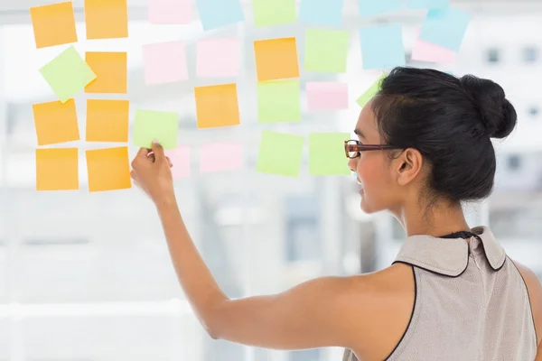 Designer looking at sticky notes on window — Stock Photo, Image