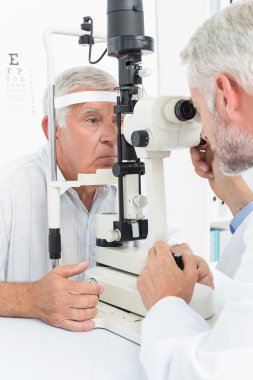 Optometrist doing sight testing for senior patient clipart
