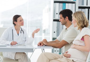Dynaecologist discussing with expectant couple clipart