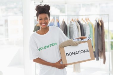 Smiling young woman with clothes donation clipart