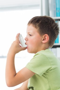 Boy using asthma inhaler in hospital clipart