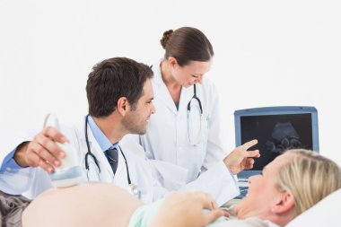 Pregnant blonde woman having an ultrasound scan clipart
