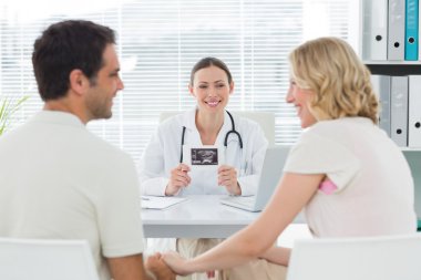 Gynaecologist looking at expectant couple clipart