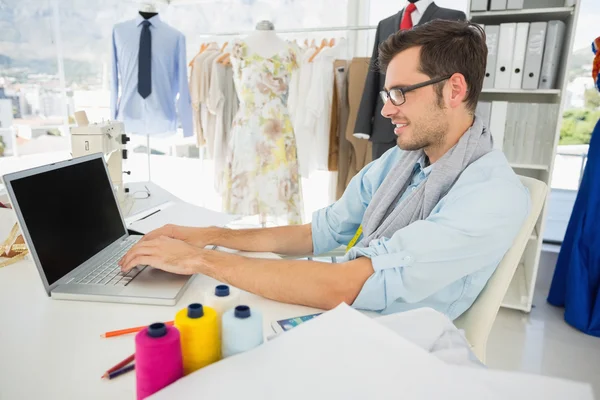 Geconcentreerde jonge mannelijke mode ontwerper met behulp van laptop — Stockfoto