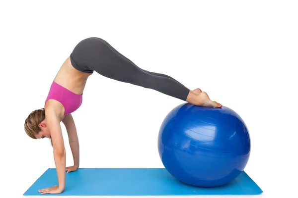 Vista lateral de una mujer en forma estirándose en la pelota de fitness —  Fotos de Stock