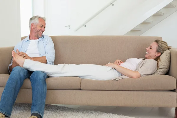 L'uomo premuroso che dà al suo partner un massaggio ai piedi sul divano — Foto Stock