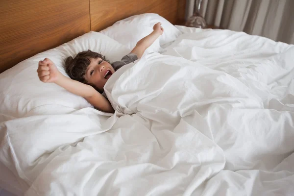 Pojke gäspningar medan stretching vapen i sängen — Stockfoto