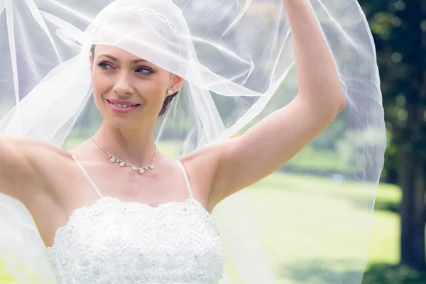 Bride lifting her veil in garden — Stock Photo, Image