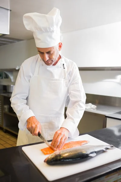 Chef masculino concentrado cortando peixe na cozinha — Fotografia de Stock