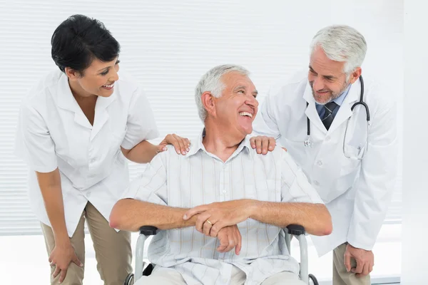 Heureux patient âgé avec des médecins assis en fauteuil roulant — Photo