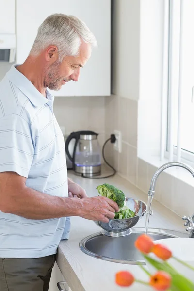 Casual man sköljer broccoli i durkslag — Stockfoto