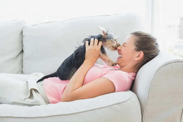 Donna felice giocando con il suo yorkshire terrier sul divano — Stok fotoğraf