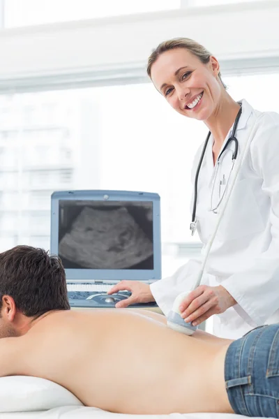 Médico realizando ecografía en la parte posterior del paciente — Foto de Stock