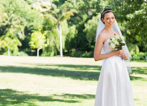 Bride holding flowers in park — Stock Photo, Image